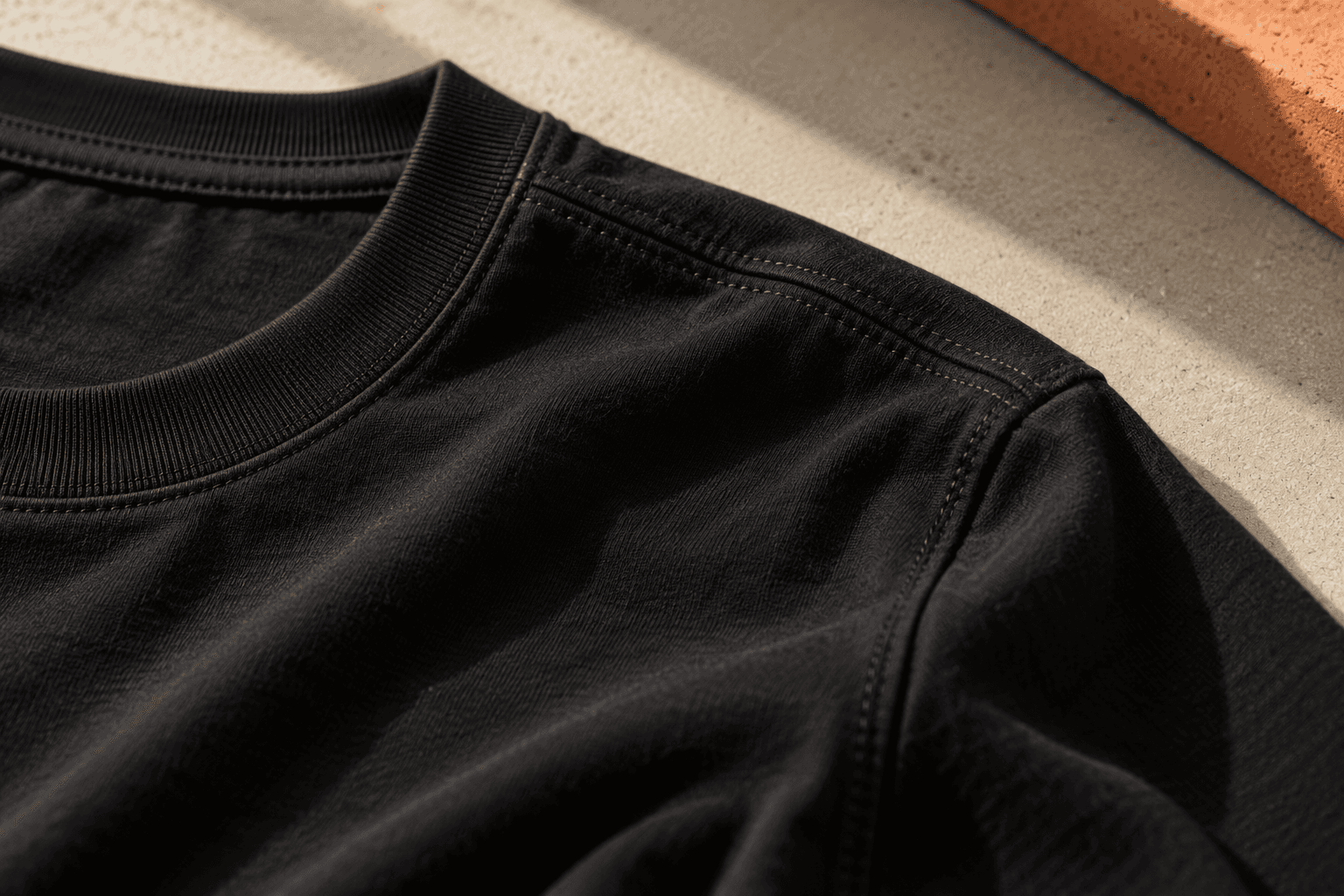 Detalhe aproximado de gola, costuras e textura de uma camiseta preta